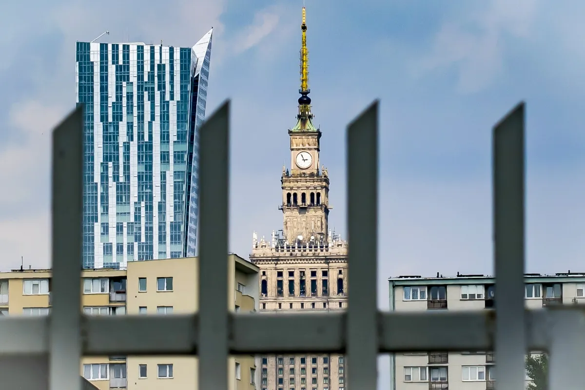 Palace of Culture and Science and a blue high-rise seen through a metal fence